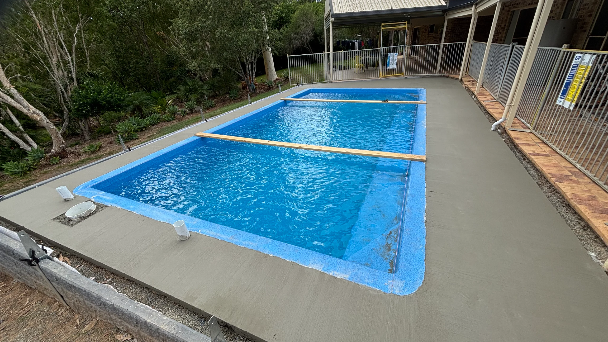 Rectangular blue fibreglass pool with freshly poured concrete surrounds as an alternative to concrete pools in Brisbane